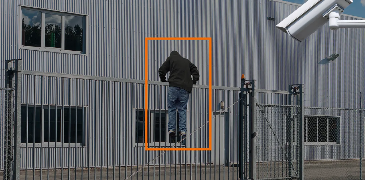 Remote guarding camera detecting a person climbing a perimeter fence at an industrial facility